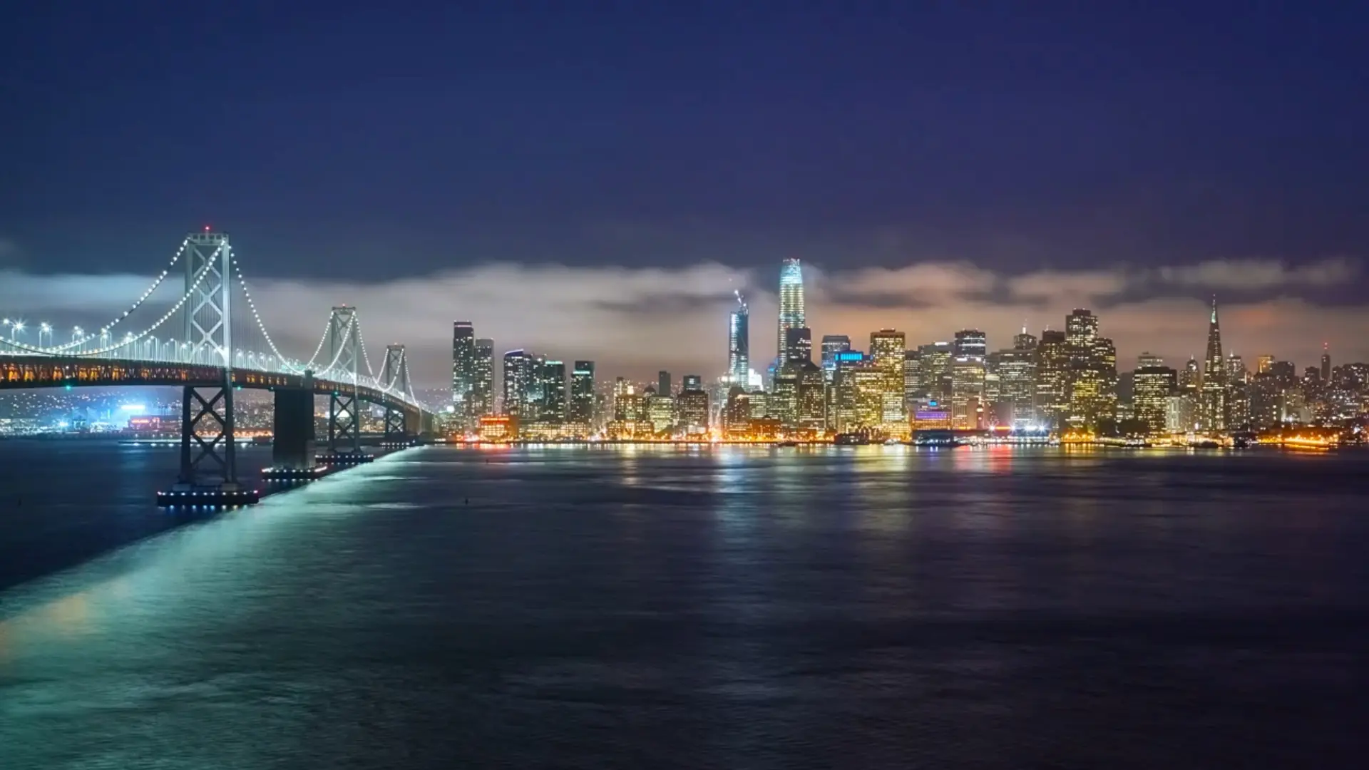 Hero A city skyline with lights at night and water.